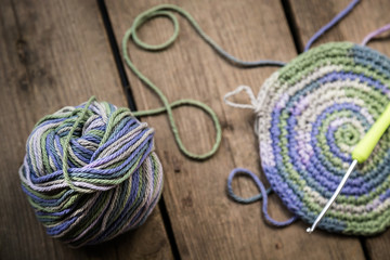 Started crocheting of rainbow threads on a wooden background. Top view. Selective focus.