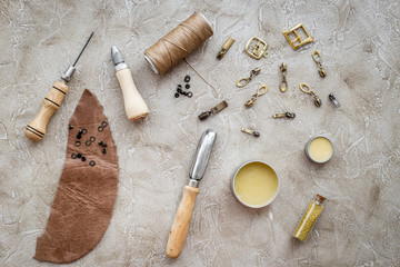 Leather craft. Tanner's tools on grey stone background top view