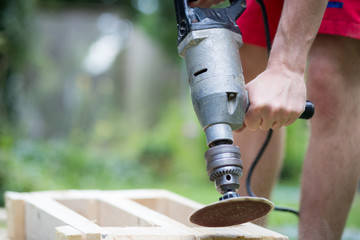 Young man hands grinding / sanding wood by automatic grinder, sawdust, woodwork, DIY