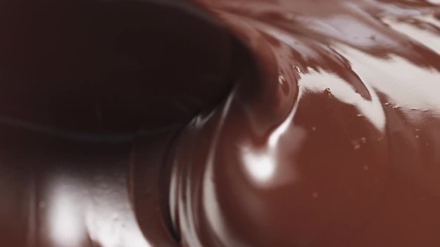 Slow motion stirring premium dark melted chocolate with big spoon