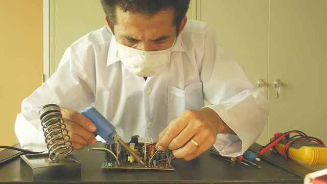 Electronics technician solder electronic circuit board.