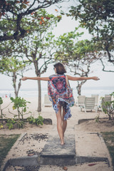 Freedom concept. Young woman in pareo and swimsuit with beach bag entering the beach. Tropical...