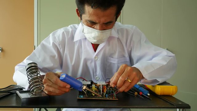 Electronics technician solder electronic circuit board.
