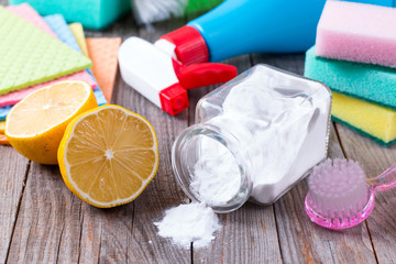 Eco-friendly natural cleaners baking soda, lemon and cloth on wooden table in hand
