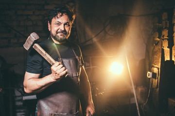 The portrait of blacksmith preparing to work metal on the anvil