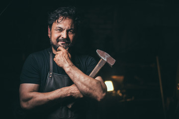 The portrait of blacksmith preparing to work metal on the anvil