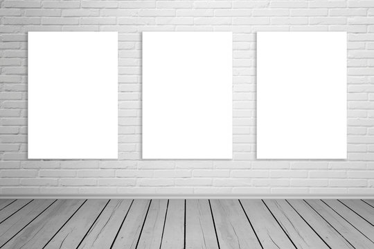 Three isolated art canvas on brick wall for mockup. Empty gallery space. Wooden floor.