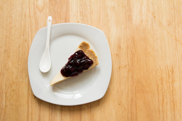 Blueberry cheese cake on white dish with spoon on wooden table background
