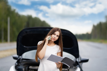 Girl near broken car on road is calling on mobile phone.