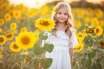 Naklejka premium Beautiful child girl in yellow garden of sunflowers