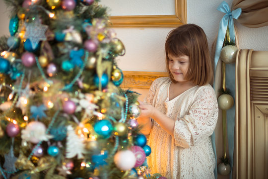 Girl kid in dress with  bear around  Christmas tree,  real interior, toning