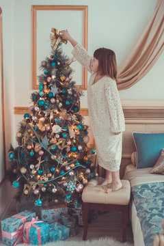 Girl kid in dress with  bear around  Christmas tree,  real interior, toning