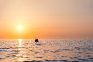 Scenic sunset over the Adriatic Sea with a silhouette of people on a boat.
