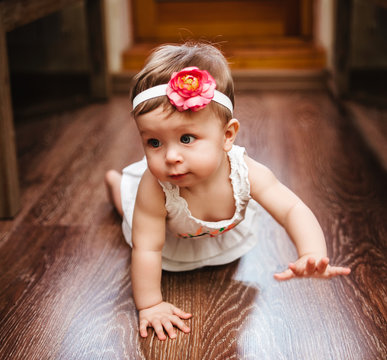 Small cute baby girl  with Bandage with flower crawls on the floor