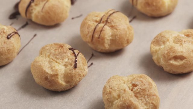 Slow motuion decorating profiteroles with fine dark chocolate on parchment paper