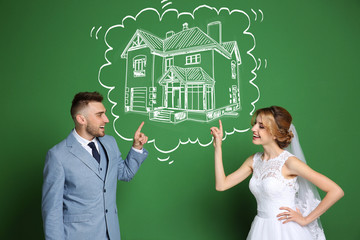 Happy wedding couple dreaming about house and drawing on color background