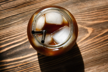 Jar with cold brew coffee on wooden table, top view