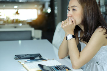 Sad Woman Sitting On chair With calculator And note book account by serious expenses