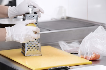 Female chef grating lemon peel in kitchen