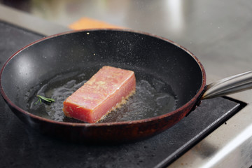 Frying pan with delicious tuna fillet on stove