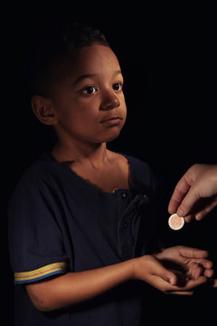 Cute little boy asking for handout on dark background. Poverty concept