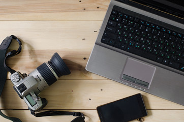 Camera and laptop on wooden background.