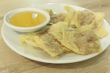 bean curd skin pork roll with plum sauce on white dish and wood table