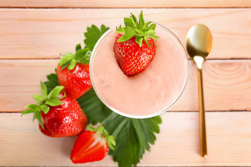 Composition with glass of fresh homemade yogurt and strawberries on wooden background