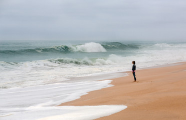 Young woman walking alone on the deserted coast of the Atlantic Ocean, Portugal