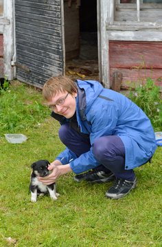 Young man playing with small monthly puppy of Lapland Reindeer dog
