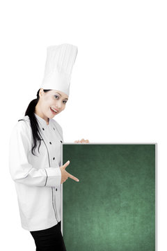 Beautiful chef pointing a blank chalkboard