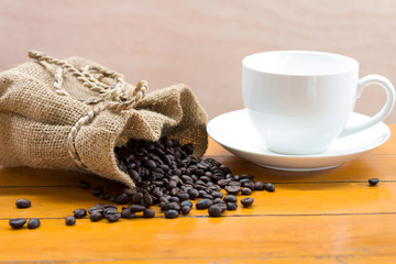 Coffee beans in sacks and white cups on wooden boards