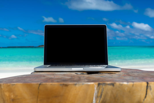 laptop blank screen on wooden desk with beach. relax concept. © gawriloff