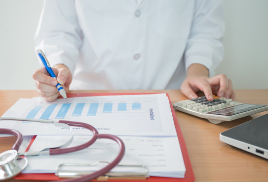 Health care costs concept picture : Hand of female doctor used a calculator for medical costs. Stethoscope and calculator on a medical chart ,symbol for health care costs or medical insurance.