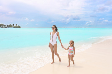 Naklejka premium Beautiful young woman with her daughter on beach at sea resort