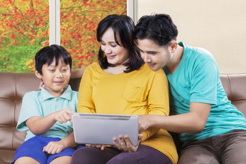 Fototapeta premium Family sitting on sofa with digital tablet