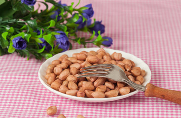 ground nut in white dish with folk on table cloth background