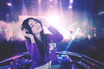 Fototapeta na wymiar Pretty DJ enjoying music in the nightclub