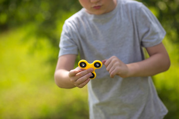 The boy holds a yellow fidget hand spinner