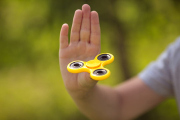 The boy holds a yellow fidget hand spinner