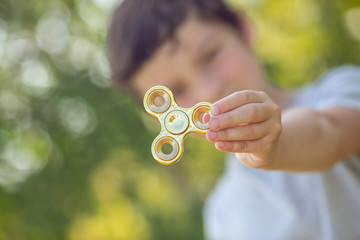 The boy holds a golden fidget hand spinner