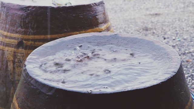 Raindrop falling to bottom of big earthen jar