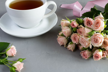Pink roses and tea on the grey background