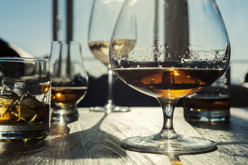 Multiple alcoholic drinks on wooden table with sunlight filtering through