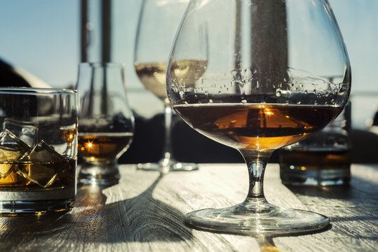 Multiple Alcoholic Drinks On Wooden Table With Sunlight Filtering Through