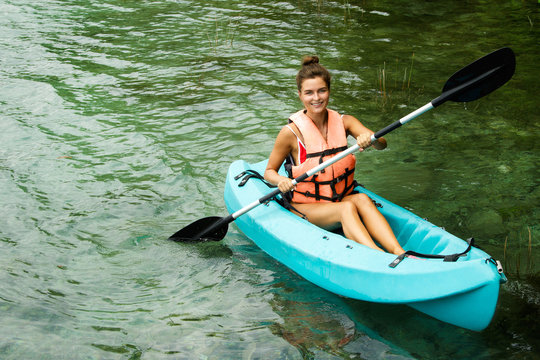 Happy young woman kayaking on the lake