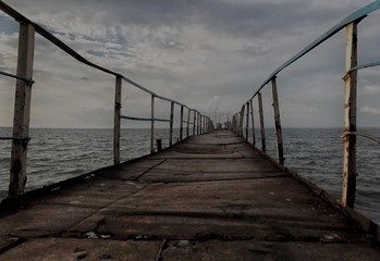 Fototapeta na wymiar The old gloomy abandoned wooden bridge