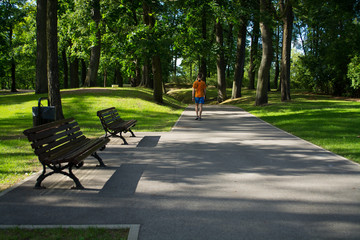 Wooden benches in a city park. Sportsman is walking  in the park.