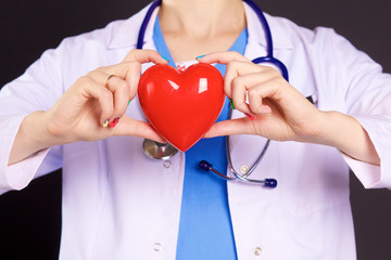 Female doctor with the stethoscope holding heart