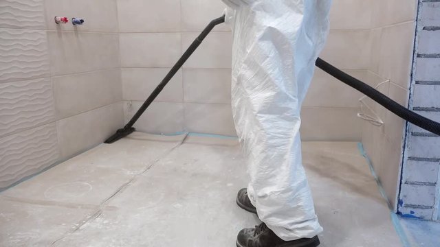 Worker man in white overall clean construction remains and dust vacuum cleaner